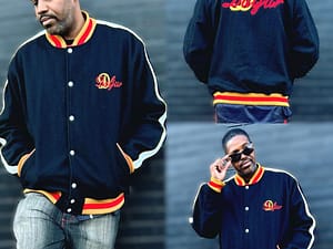 Man showcasing a stylish navy varsity jacket with orange and white accents.