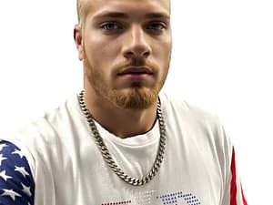 Young man with blond hair wearing a white shirt and chain necklace.
