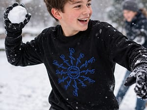 Boy teen wearing a black long sleeve t-shirt with a graphic snowflake pattern.